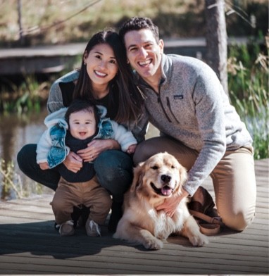 smiling husband, wife and child with dog